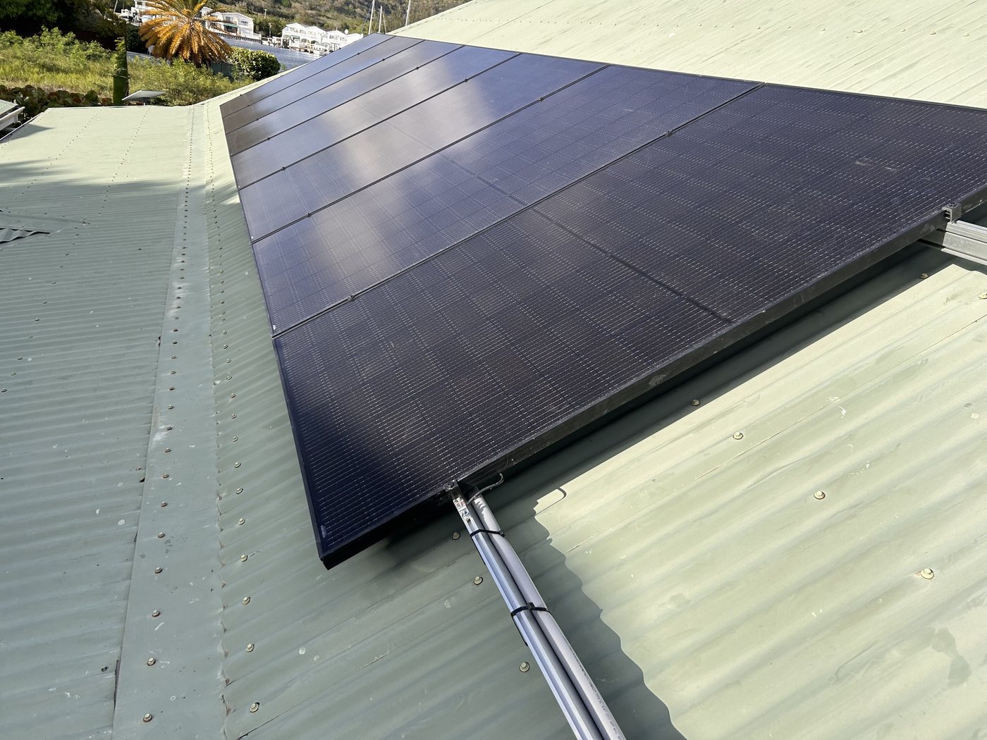 Solar panel array installed on an Antigua rooftop, overlooking the water